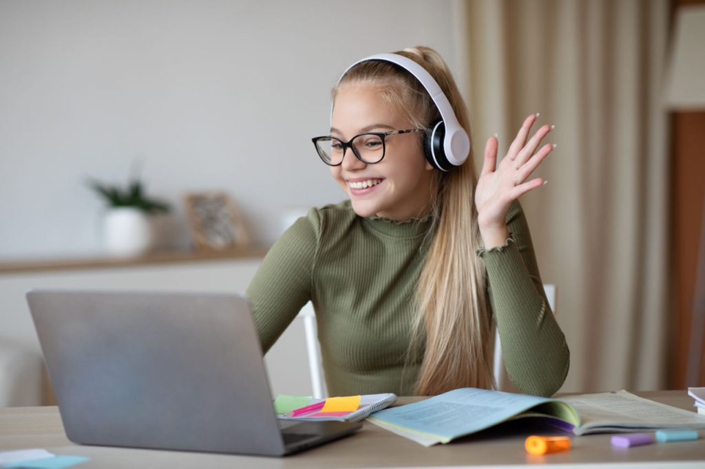 Child With Headphones Waving At Laptop